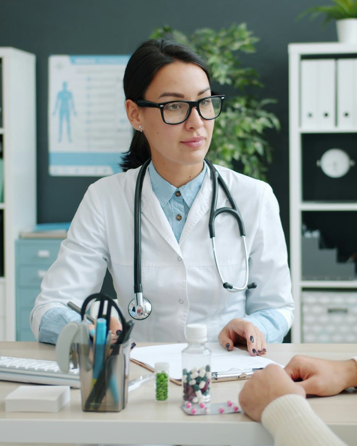 A consultant physician talking with a patient across her desk at General Hospital